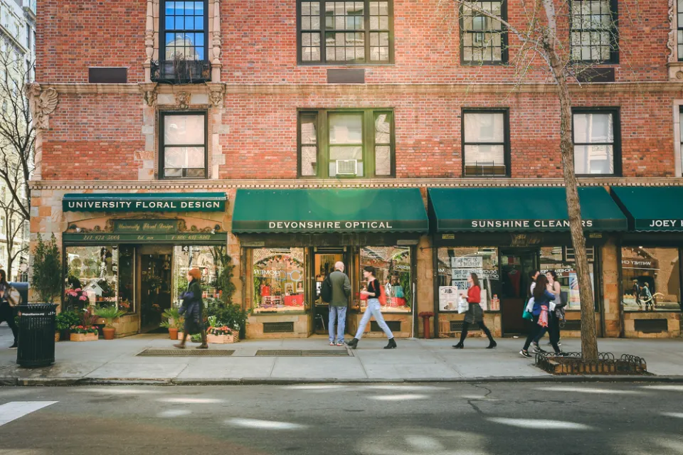 Greenwich Village street with red brick buildings with green awnings and businesses on first floor